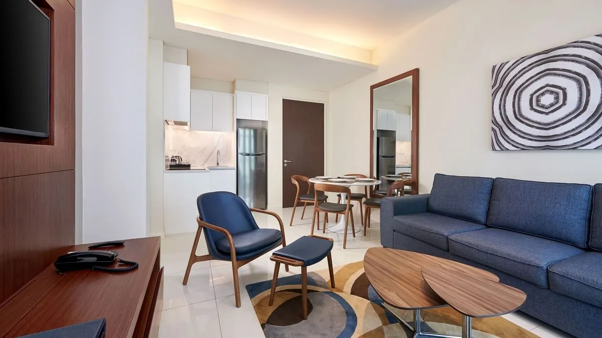 Duo Suite: Living room with a blue sofa and lounge chair, open to the kitchen