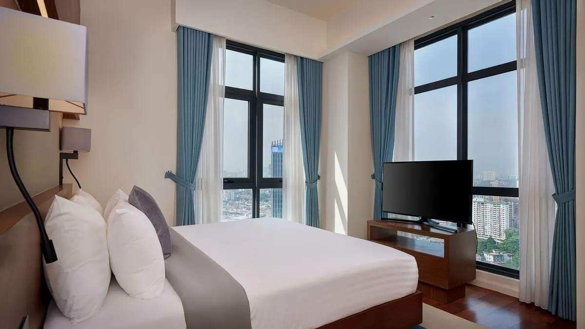 Duo Suite: King-sized bed facing a flat-screen TV and city-view windows