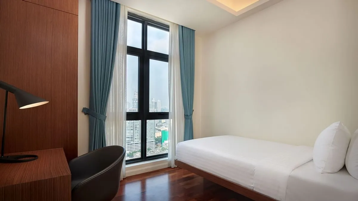 Duo Suite: Single bed by the window with an armchair and floor lamp