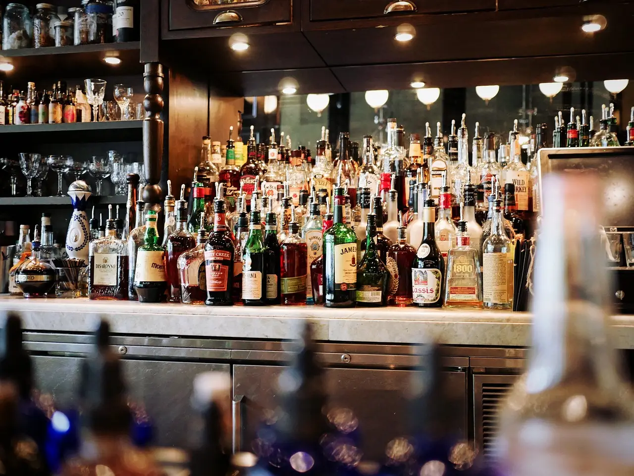Shelves of spirits lit behind a cocktail bar