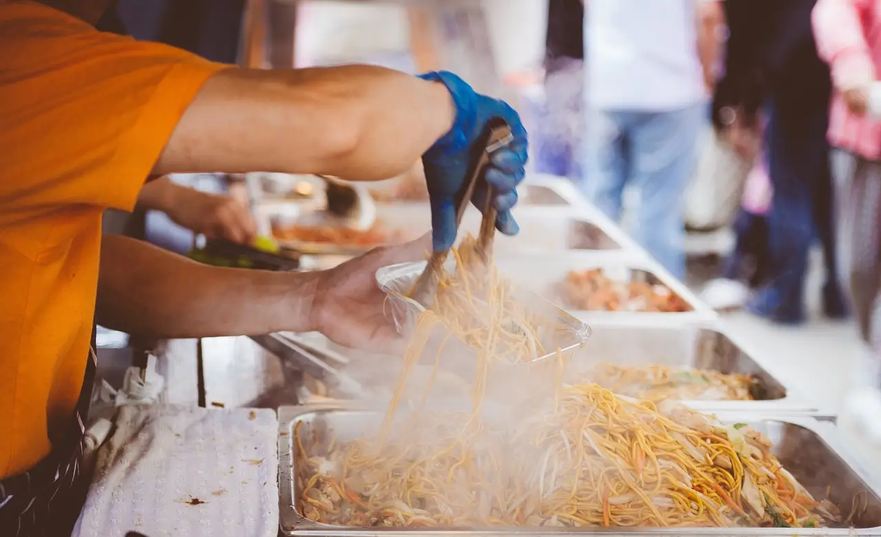 Noodles being tossed in steaming trays at a Kuala Lumpur street food stall